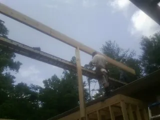 Carpenter setting a ridge beam over a new addition frame — Ice Dam Removal by Roofing Brothers in Tome