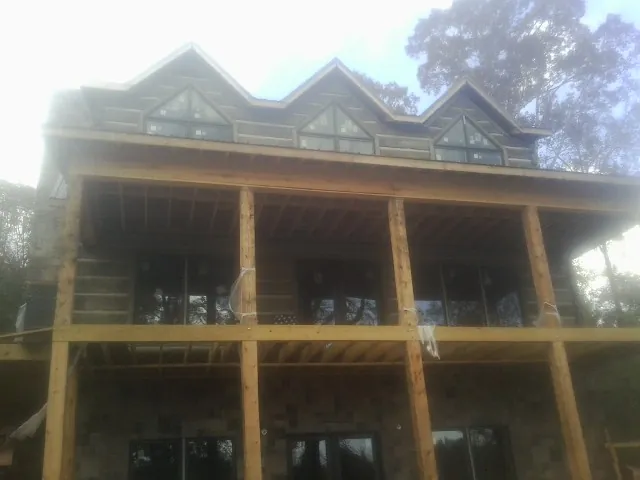 Dormers and porch framing on a large log home under construction — Roof Coating work by our crew in Tome