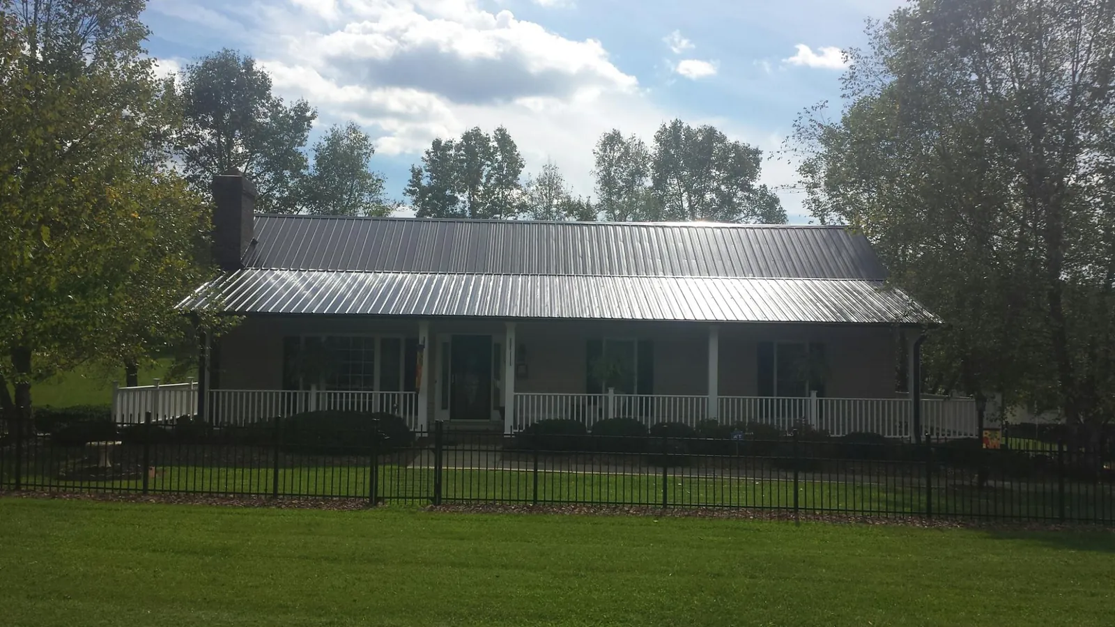 Gray metal roof on a brick ranch with a full width front porch — Gutter Guard Installation work by our crew in Tome