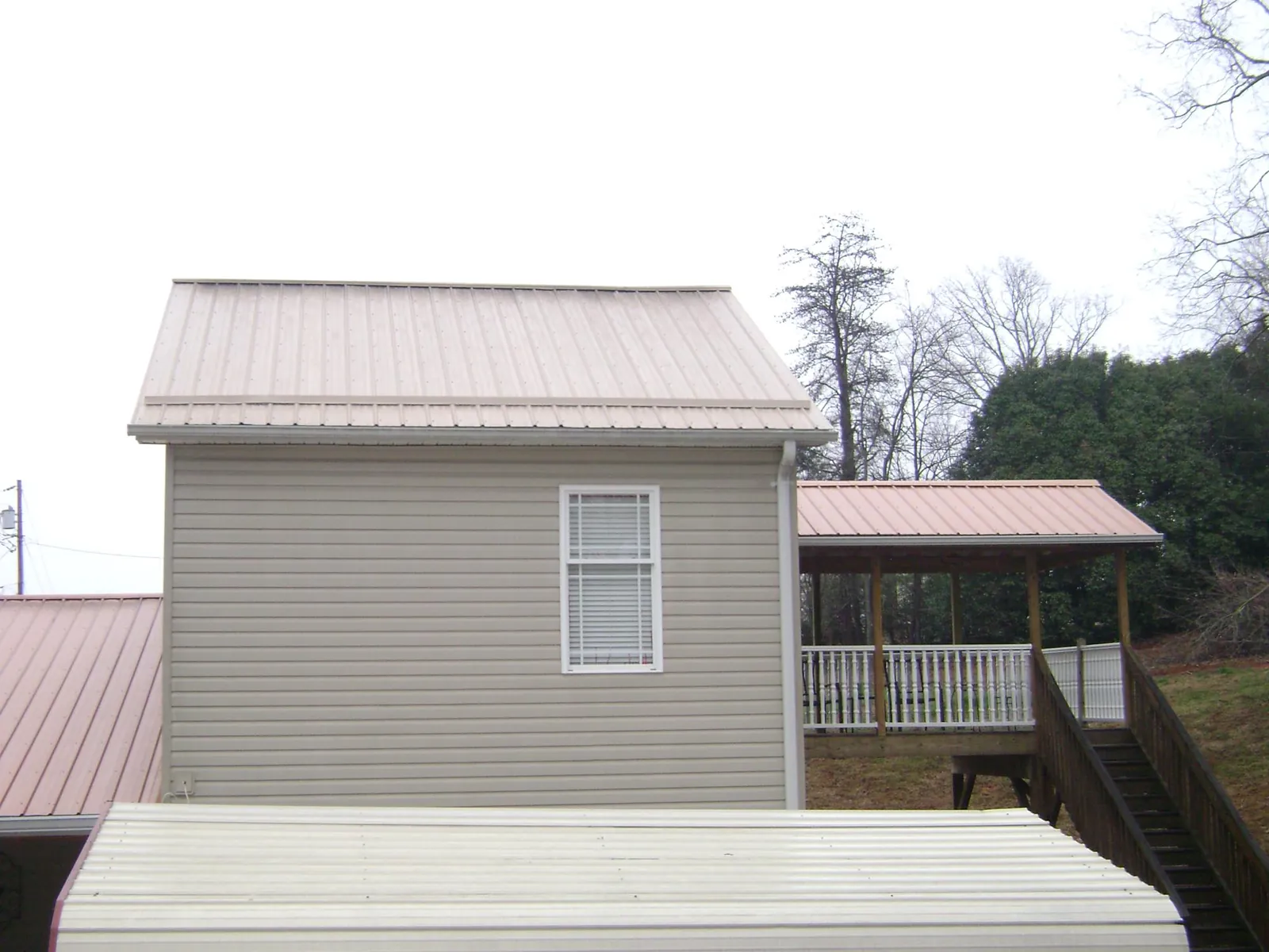 Tan metal roofs on a two story addition and attached porch, from a Roof Replacement job in Tome