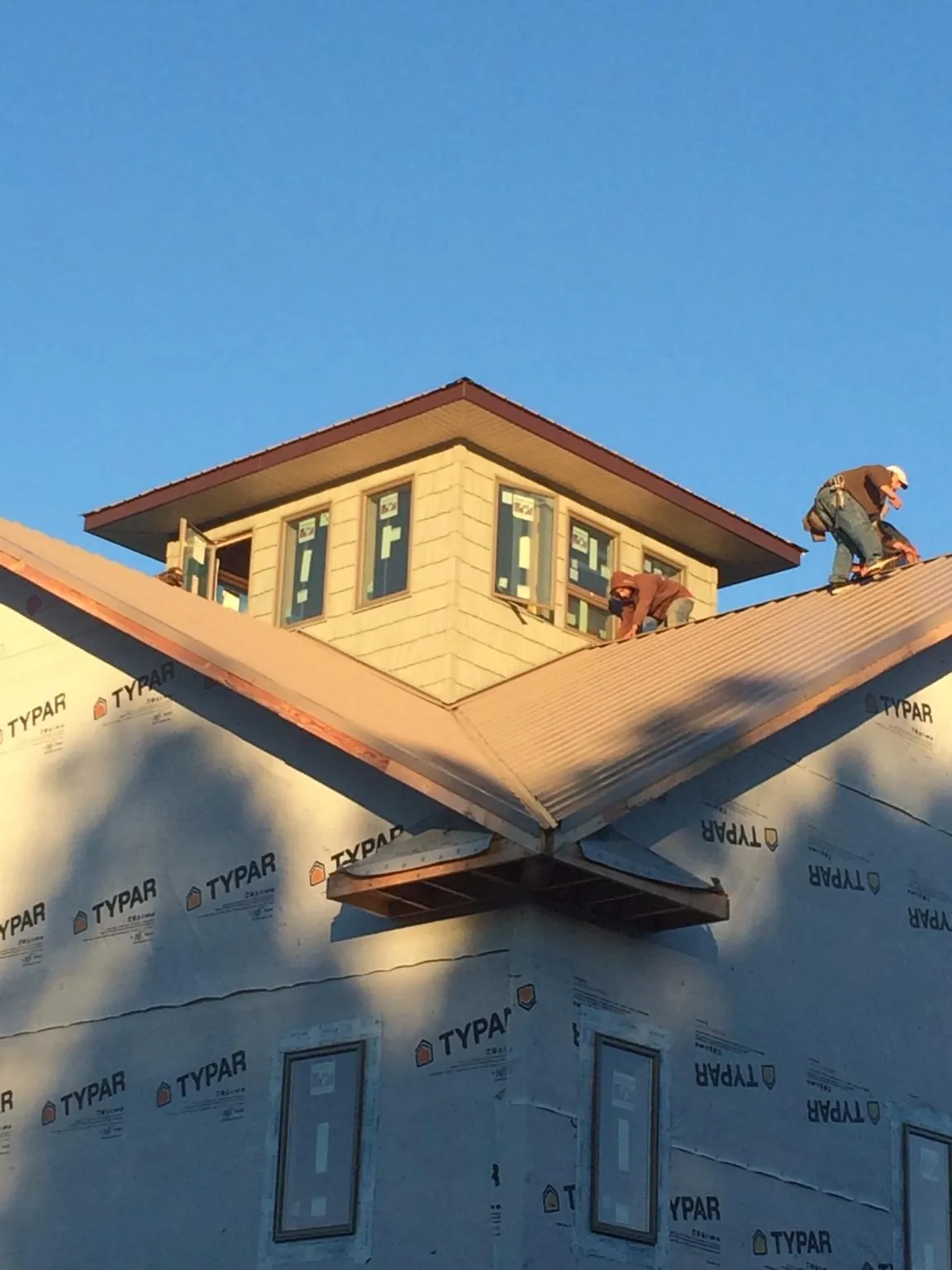 Roofers working around a rooftop cupola on a new metal roof at sunset — Roof Waterproofing in Tome by Roofing Brothers